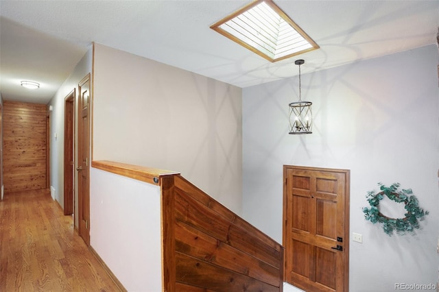 hall featuring a notable chandelier, light hardwood / wood-style floors, and a skylight