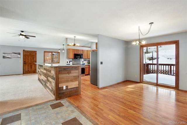 kitchen with appliances with stainless steel finishes, a healthy amount of sunlight, ceiling fan with notable chandelier, and decorative light fixtures