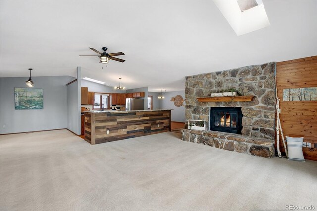 living room featuring vaulted ceiling, wooden walls, light colored carpet, and a fireplace