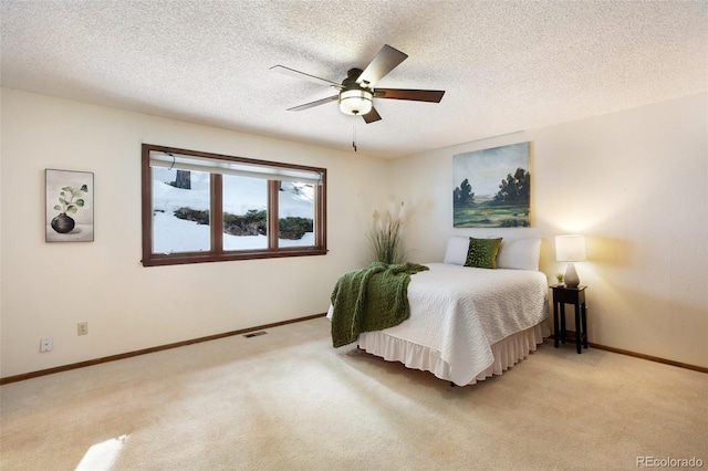 bedroom featuring ceiling fan, light colored carpet, and a textured ceiling