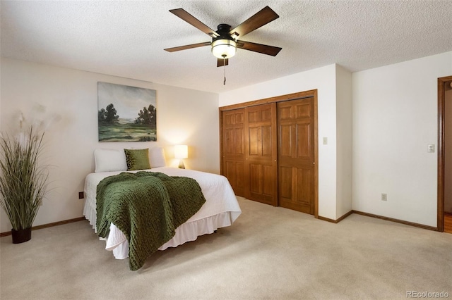 bedroom with ceiling fan, light colored carpet, a closet, and a textured ceiling