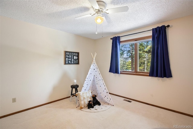 game room featuring ceiling fan, a textured ceiling, and carpet