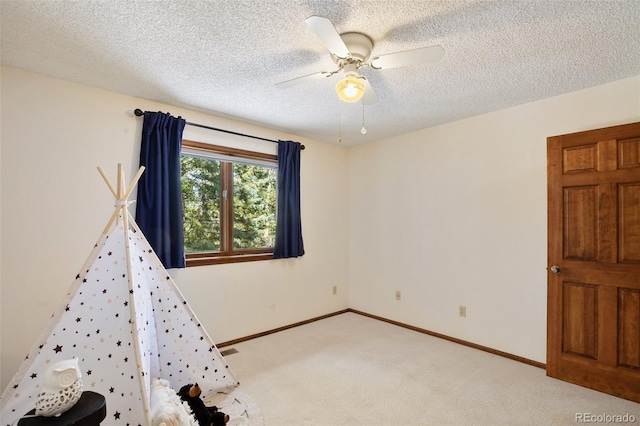 interior space featuring ceiling fan, light colored carpet, and a textured ceiling