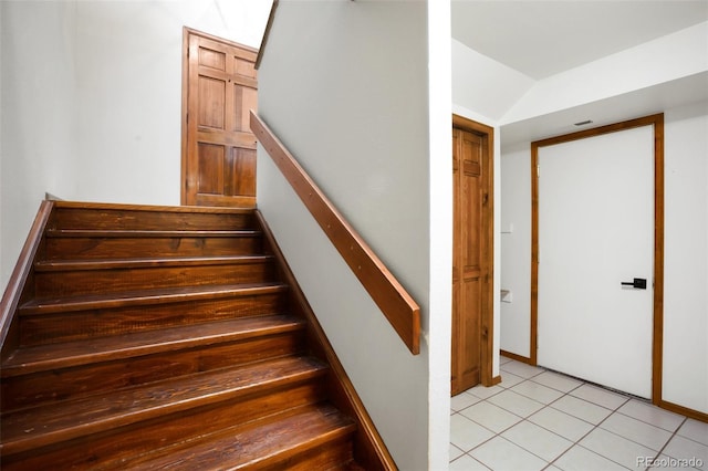 stairway featuring lofted ceiling and tile patterned floors