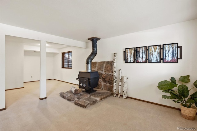 basement featuring light colored carpet and a wood stove