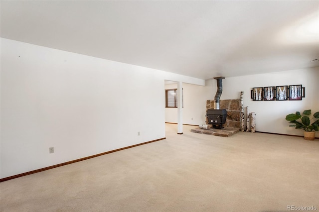 unfurnished living room featuring light colored carpet and a wood stove