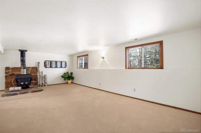 unfurnished living room with plenty of natural light, carpet floors, and a wood stove