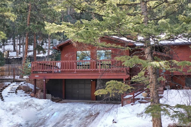 snow covered house with a garage and a deck