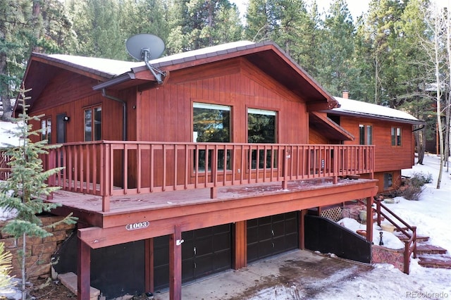 1003 Kings Crown Rd, Woodland Park, CO 80863 - snow covered back of property featuring an attached garage, a deck, and a view of trees
