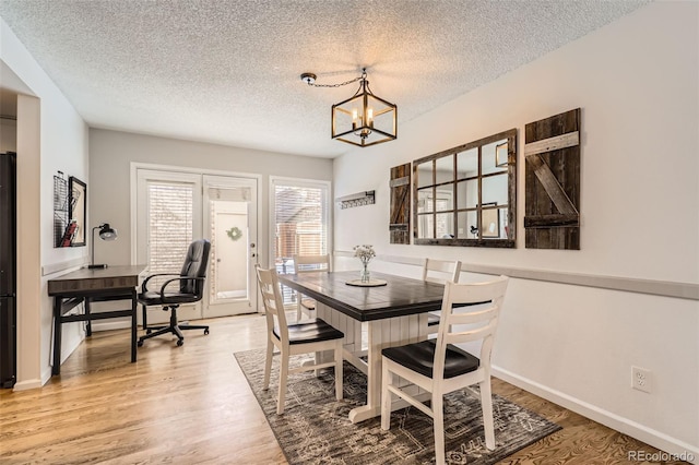 dining area featuring a notable chandelier, hardwood / wood-style flooring, and a textured ceiling