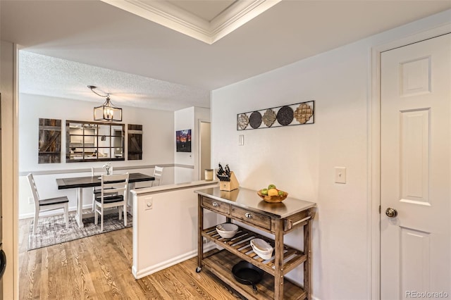 kitchen with a notable chandelier, light hardwood / wood-style flooring, ornamental molding, and a textured ceiling