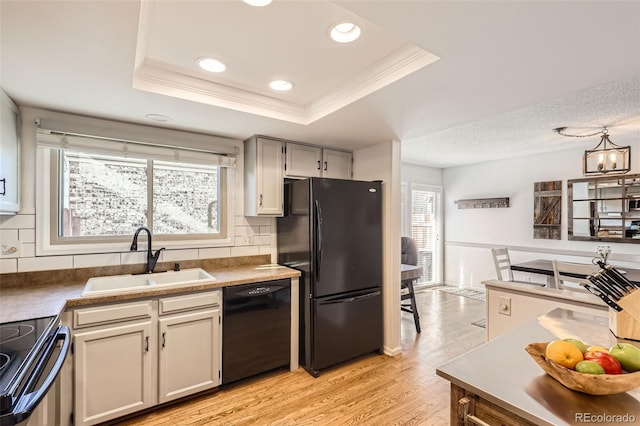 kitchen with a healthy amount of sunlight, a raised ceiling, sink, and black appliances