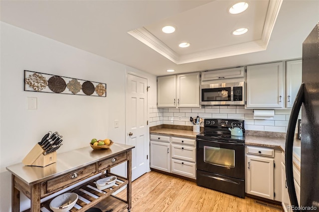 kitchen featuring a raised ceiling, crown molding, backsplash, and black appliances