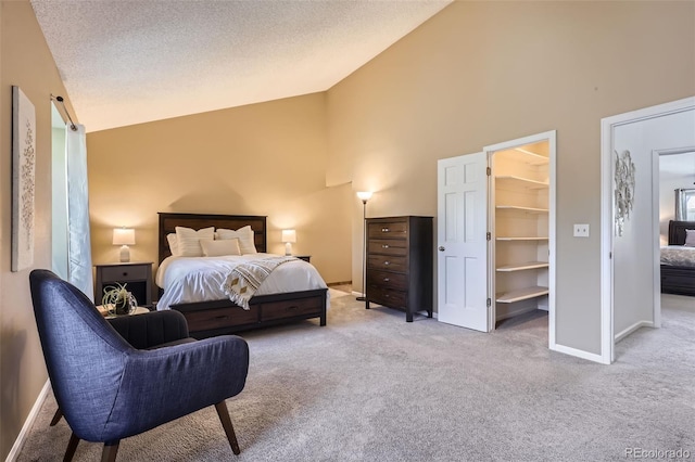 carpeted bedroom featuring a spacious closet, high vaulted ceiling, and a textured ceiling