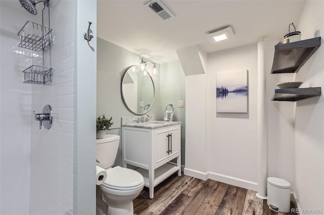 bathroom featuring tiled shower, vanity, toilet, and hardwood / wood-style floors