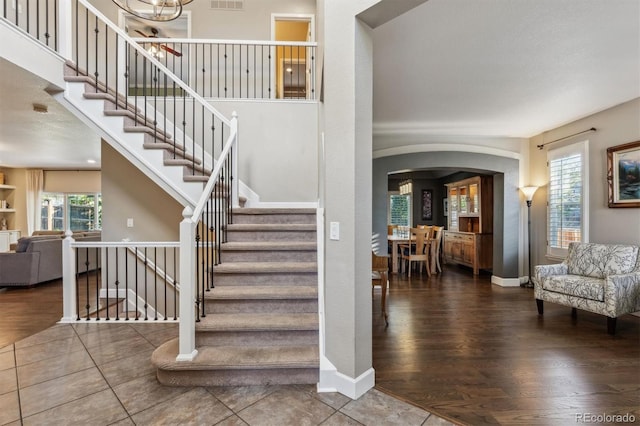 stairway with arched walkways, healthy amount of natural light, wood finished floors, and baseboards
