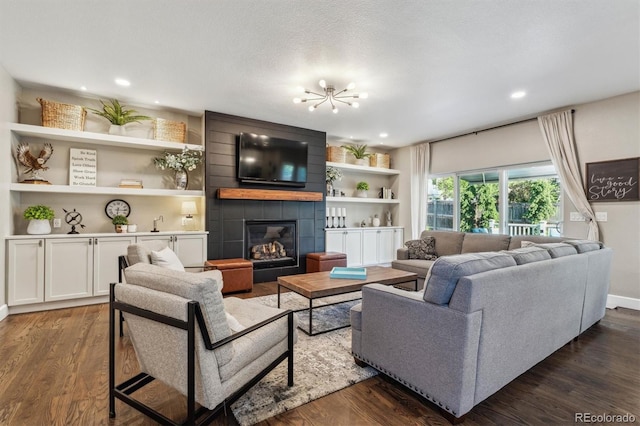 living room with a tiled fireplace, dark wood finished floors, a chandelier, recessed lighting, and baseboards