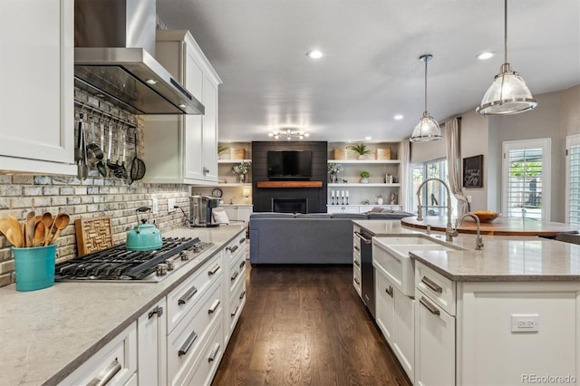 kitchen with wall chimney range hood, stainless steel gas cooktop, white cabinets, tasteful backsplash, and dark wood-style floors