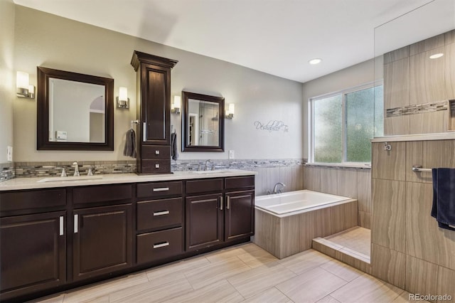 full bathroom featuring a bath, double vanity, and a wainscoted wall