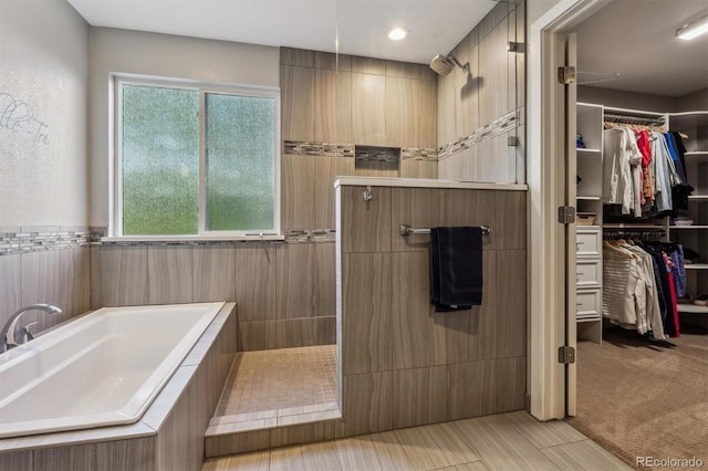 full bath with a bath, walk in shower, and a walk in closet