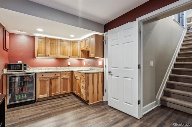 kitchen with beverage cooler, dark wood-type flooring, stainless steel microwave, light stone countertops, and recessed lighting