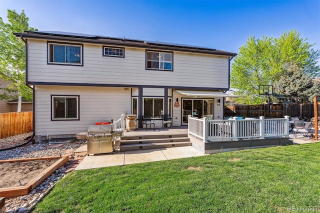 rear view of property with roof mounted solar panels and a deck