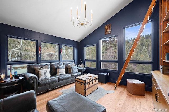 living room featuring vaulted ceiling, a chandelier, and light hardwood / wood-style floors