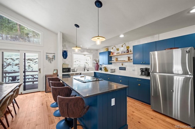 kitchen featuring vaulted ceiling, a center island, light hardwood / wood-style floors, black appliances, and blue cabinetry