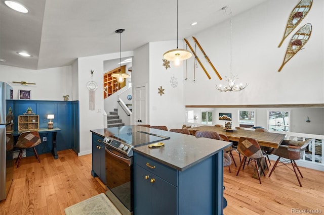 kitchen with stainless steel range with electric stovetop, blue cabinets, decorative light fixtures, and light hardwood / wood-style flooring