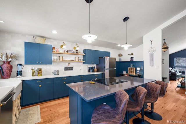 kitchen featuring blue cabinets, a kitchen bar, stainless steel fridge, dishwasher, and black electric stovetop