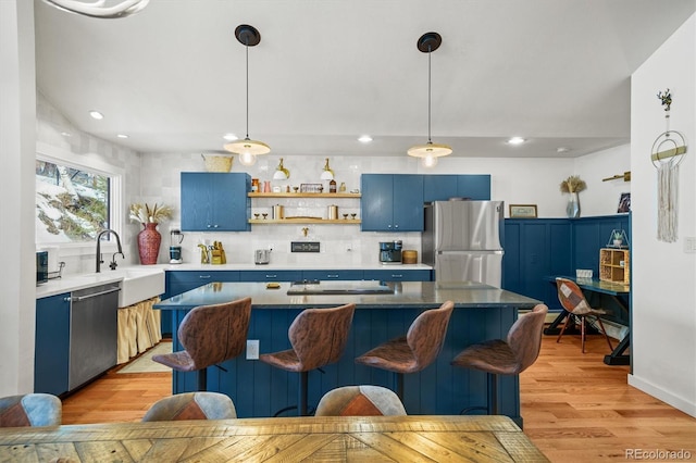 kitchen featuring blue cabinetry, appliances with stainless steel finishes, light hardwood / wood-style floors, and sink