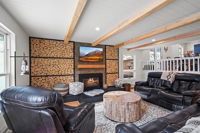 living room featuring beamed ceiling and a stone fireplace