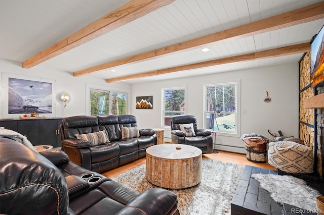 living room with a stone fireplace, plenty of natural light, beamed ceiling, and light wood-type flooring