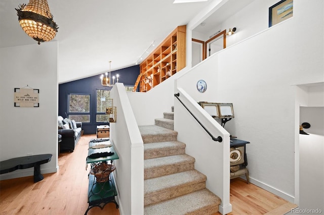 stairway featuring a notable chandelier, wood-type flooring, and high vaulted ceiling