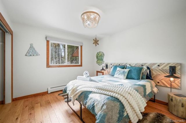 bedroom featuring wood-type flooring, a closet, and baseboard heating