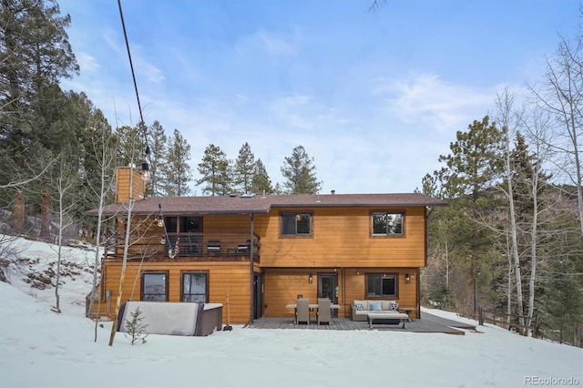 snow covered rear of property with a balcony and a deck