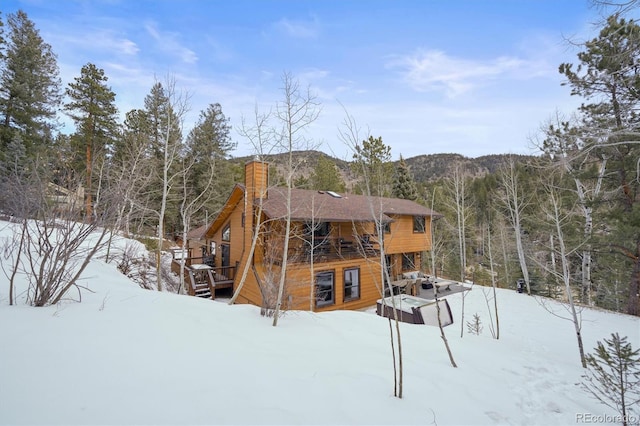 snow covered house with a deck with mountain view