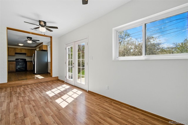 7065 Ingalls Ct, Arvada, CO 80003 - unfurnished living room featuring a wood stove, light wood-type flooring, a ceiling fan, french doors, and baseboards