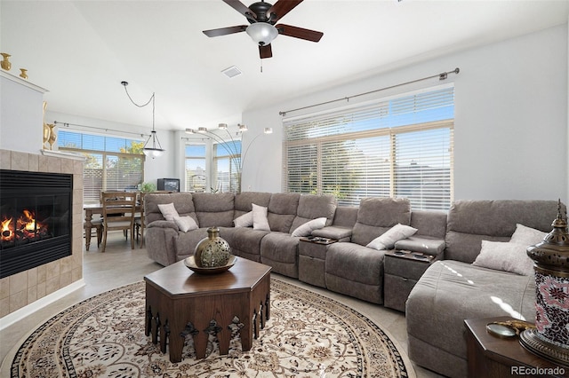 living room with a tile fireplace and ceiling fan