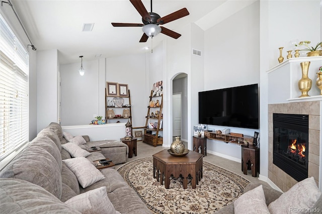 carpeted living room featuring high vaulted ceiling, a fireplace, and ceiling fan