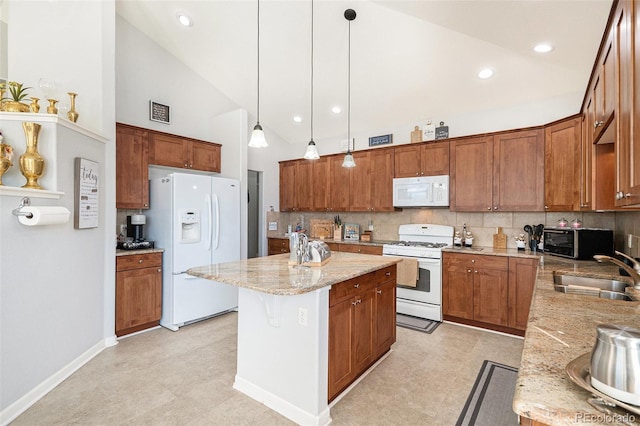 kitchen with light stone countertops, sink, pendant lighting, a center island, and white appliances