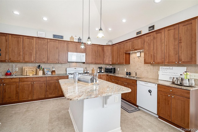 kitchen featuring hanging light fixtures, light stone countertops, a kitchen island with sink, sink, and white appliances