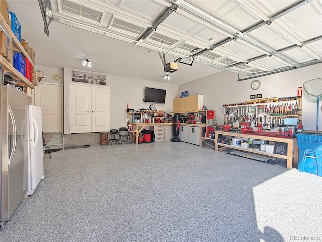 garage with a garage door opener, a workshop area, and stainless steel refrigerator