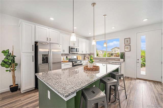 2054 S Upham Way, Denver, CO 80227 - kitchen featuring stainless steel appliances, wood finished floors, a kitchen island, white cabinetry, and recessed lighting