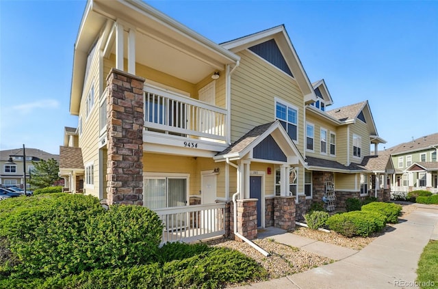 9434 Ashbury Cir Unit 203, Parker, CO 80134 - view of front of house featuring stone siding, a balcony, a residential view, and covered porch