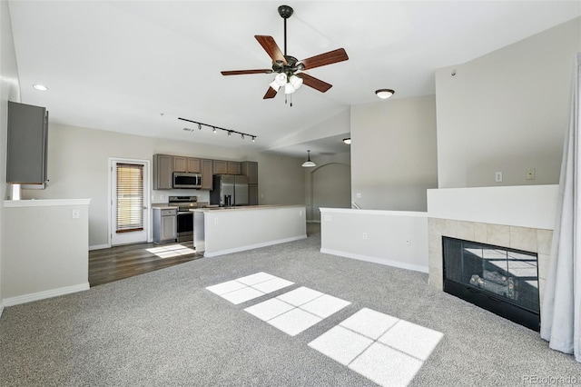 9434 Ashbury Cir Unit 203, Parker, CO 80134 - unfurnished living room with carpet flooring, vaulted ceiling, ceiling fan, baseboards, and rail lighting