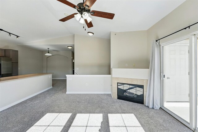 9434 Ashbury Cir Unit 203, Parker, CO 80134 - unfurnished living room with carpet floors, ceiling fan, baseboards, lofted ceiling, and a tile fireplace