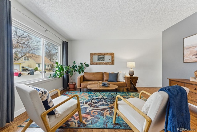 living area featuring a textured ceiling, baseboards, and wood finished floors