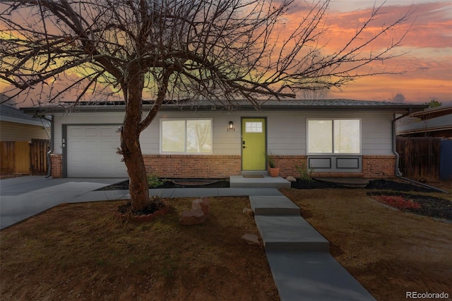 single story home with a garage, concrete driveway, brick siding, and fence