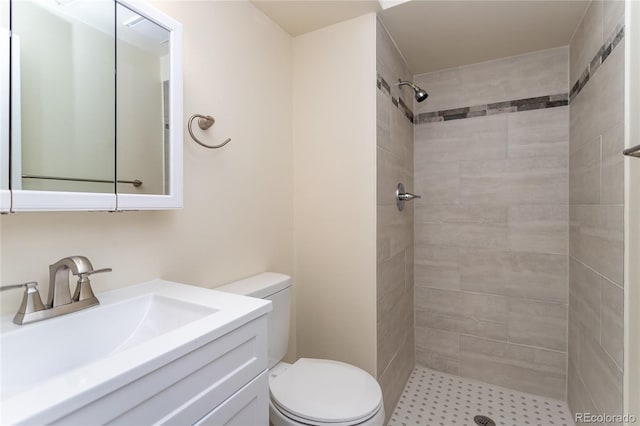 bathroom with a tile shower, vanity, and toilet